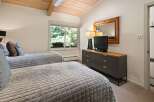 This charming bedroom features two comfortable beds with quilted grey comforters and decorative pillows, perfect for a restful night's sleep.