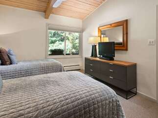 This charming bedroom features two comfortable beds with quilted grey comforters and decorative pillows, perfect for a restful night's sleep.