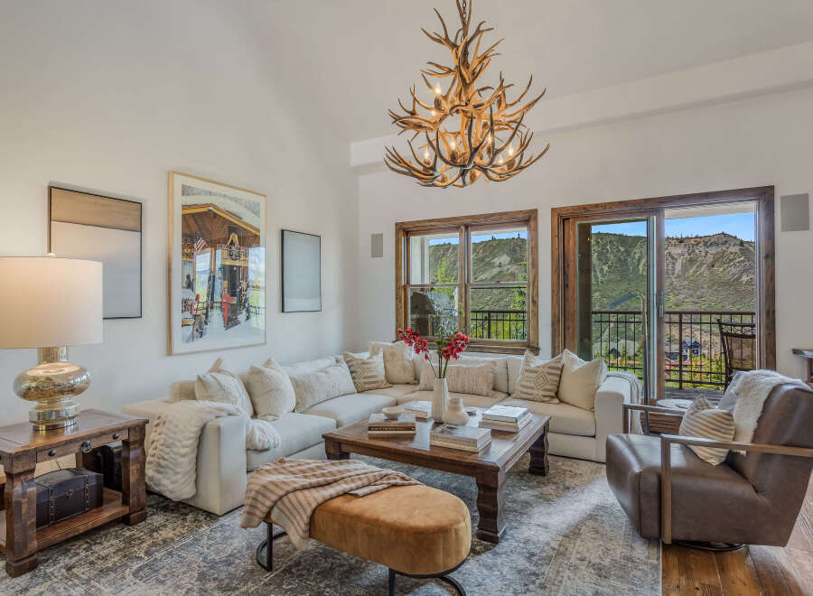 Experience luxury mountain living in this stunning living room, featuring a plush sectional sofa and a unique antler chandelier.