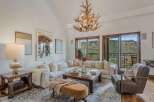 Experience luxury mountain living in this stunning living room, featuring a plush sectional sofa and a unique antler chandelier.