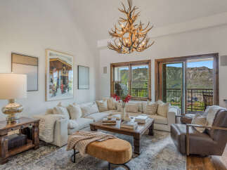 Experience luxury mountain living in this stunning living room, featuring a plush sectional sofa and a unique antler chandelier.