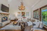 Experience rustic elegance in this spacious living room, featuring a grand stone fireplace and a unique antler chandelier.