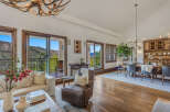 Experience luxurious mountain living in this stunning open-concept great room, featuring a rustic antler chandelier and expansive windows with breathtaking views.