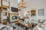 Experience rustic luxury in this stunning living room, featuring a grand stone fireplace and a unique antler chandelier.