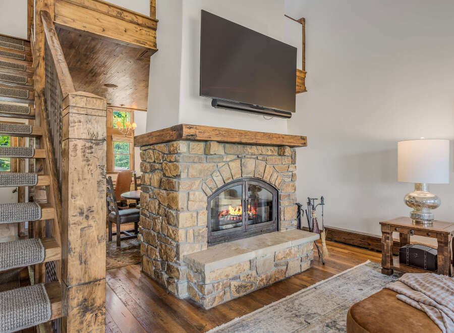 Experience rustic charm and modern comfort in this inviting living space, featuring a magnificent stone fireplace with a rustic wood mantel, perfect for cozy evenings.