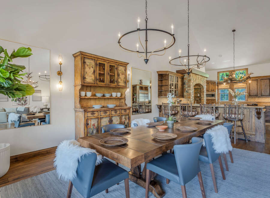 Experience elegant dining in this spacious room, featuring a large wooden table set for gatherings and a rustic hutch for storage.
