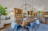 Experience elegant dining in this spacious room, featuring a large wooden table set for gatherings and a rustic hutch for storage.