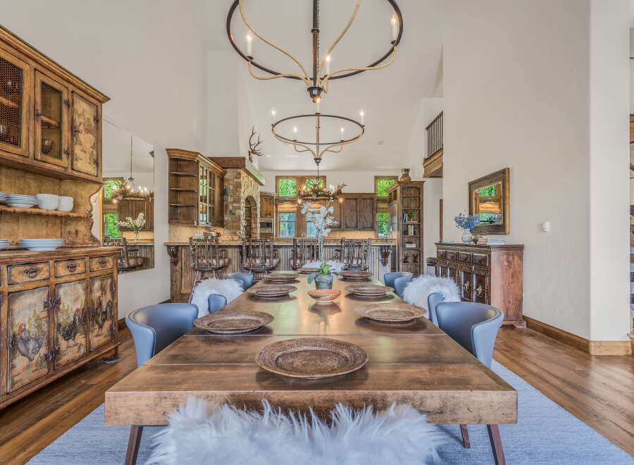 Experience rustic charm in this spacious dining room, featuring a large wooden table set for a feast and surrounded by plush seating.