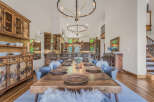Experience rustic charm in this spacious dining room, featuring a large wooden table set for a feast and surrounded by plush seating.