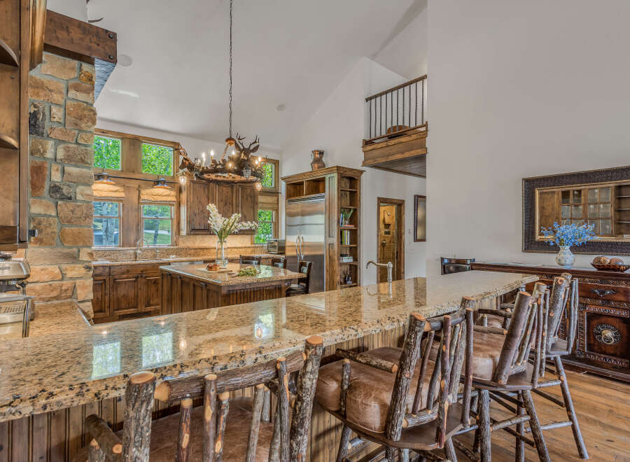 Experience rustic luxury in this stunning kitchen featuring a grand stone fireplace and rich wood cabinetry.