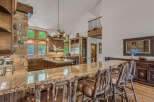 Experience rustic luxury in this stunning kitchen featuring a grand stone fireplace and rich wood cabinetry.