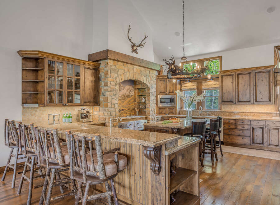 Experience rustic elegance in this stunning kitchen, featuring custom wood cabinetry and a grand stone archway.