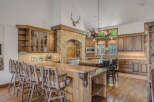 Experience rustic elegance in this stunning kitchen, featuring custom wood cabinetry and a grand stone archway.