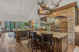 Experience rustic luxury in this stunning mountain kitchen, featuring a grand stone fireplace and a unique antler chandelier.