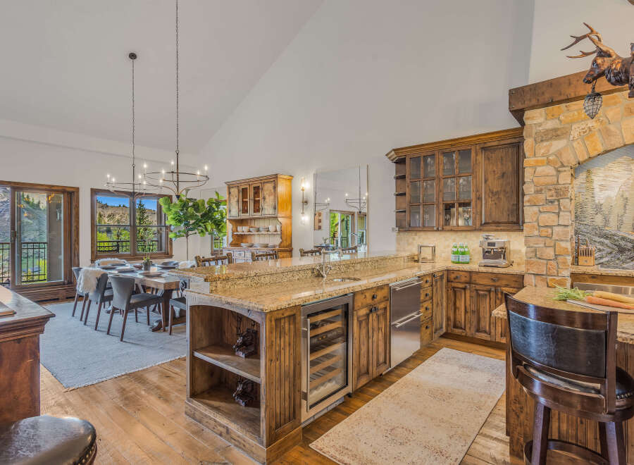 Experience rustic elegance in this stunning mountain home, featuring a gourmet kitchen with custom wood cabinetry, granite countertops, and a wine cooler.