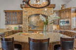Experience luxury in this stunning kitchen featuring custom wood cabinetry and a grand stone fireplace with an intricate mosaic backsplash.