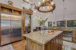 Experience rustic luxury in this stunning kitchen featuring a large granite island with a cutting board and fresh bread, perfect for entertaining.