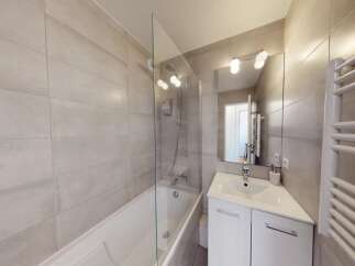This modern bathroom features a sleek bathtub with a glass shower screen, perfect for relaxing after a long day.