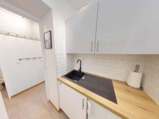 Discover this modern kitchen featuring sleek white cabinetry and a stylish black sink.