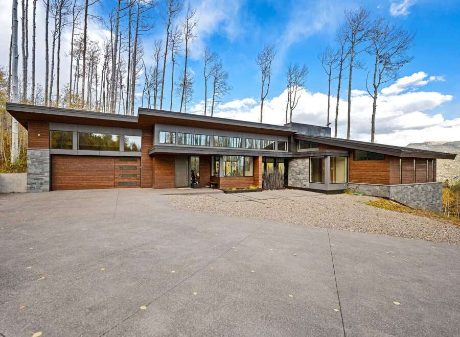 Experience modern luxury in this stunning architectural home, featuring a striking combination of wood and stone exteriors.