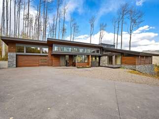 Experience modern luxury in this stunning architectural home, featuring a striking combination of wood and stone exteriors.