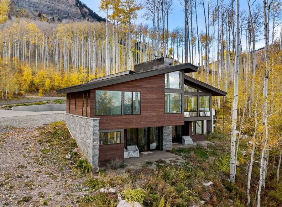 Nestled amidst a vibrant autumn aspen grove, this modern mountain home offers breathtaking views and a seamless indoor-outdoor living experience.