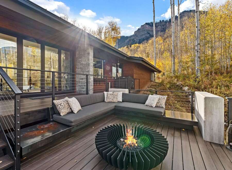 Experience the ultimate in outdoor living with this stunning deck featuring a modern sectional sofa and a captivating fire pit, perfect for cozy evenings.