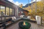 Experience the ultimate in outdoor living with this stunning deck featuring a modern sectional sofa and a captivating fire pit, perfect for cozy evenings.