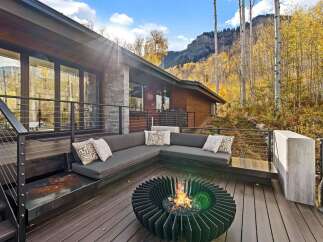 Experience the ultimate in outdoor living with this stunning deck featuring a modern sectional sofa and a captivating fire pit, perfect for cozy evenings.