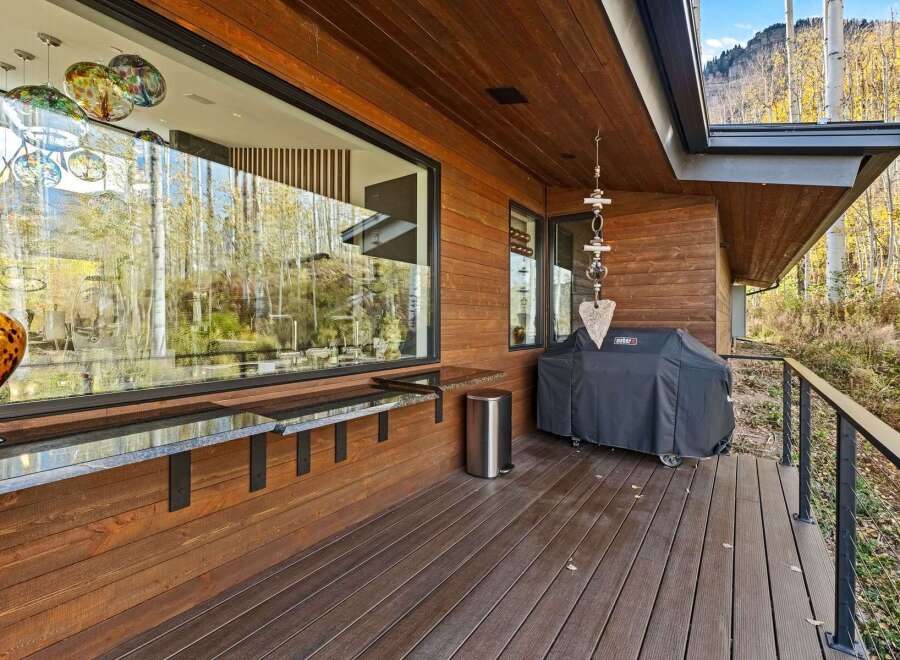 Enjoy outdoor living with this spacious deck featuring a built-in bar and a Weber grill, perfect for entertaining.