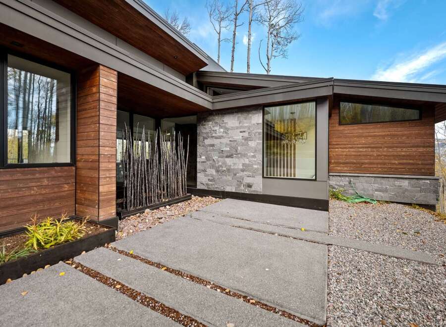 Experience modern luxury in this stunning home featuring a striking facade of warm wood and sleek stone.