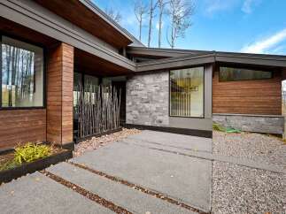 Experience modern luxury in this stunning home featuring a striking facade of warm wood and sleek stone.