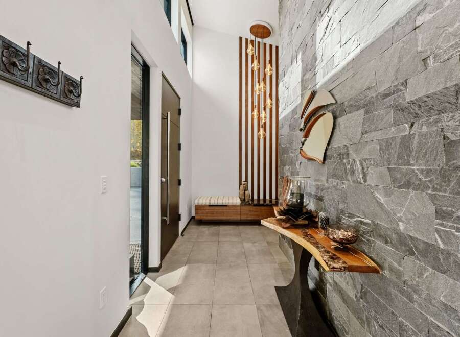 Step into a modern entryway featuring a striking stone accent wall and a unique live-edge console table.