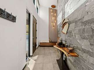 Step into a modern entryway featuring a striking stone accent wall and a unique live-edge console table.