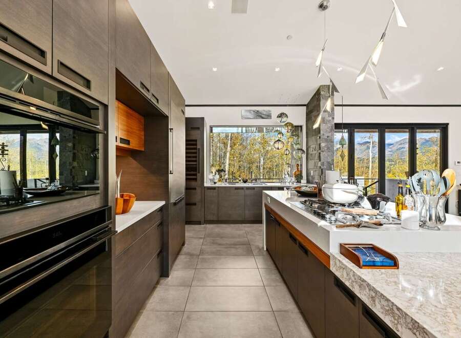 Experience luxury living in this modern kitchen featuring sleek, dark wood cabinetry and a spacious island perfect for entertaining.