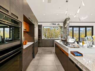 Experience luxury living in this modern kitchen featuring sleek, dark wood cabinetry and a spacious island perfect for entertaining.
