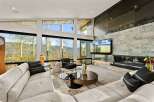 Experience breathtaking mountain views from this modern living room, featuring expansive windows that frame the vibrant autumn foliage.