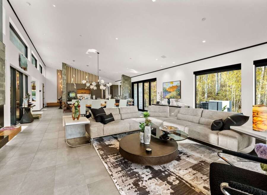 Experience luxurious open-concept living in this stunning modern home, featuring a spacious living area with a large sectional sofa and a striking abstract rug.