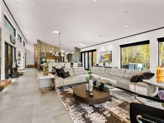 Experience luxurious open-concept living in this stunning modern home, featuring a spacious living area with a large sectional sofa and a striking abstract rug.