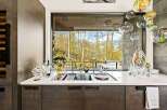Experience luxury living with this stunning kitchen featuring a large sink area overlooking a breathtaking forest view.