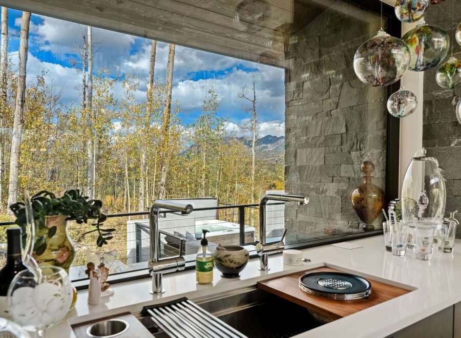 Experience luxury living with this stunning kitchen featuring a sleek countertop and modern fixtures, overlooking a breathtaking mountain landscape.
