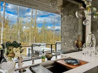 Experience luxury living with this stunning kitchen featuring a sleek countertop and modern fixtures, overlooking a breathtaking mountain landscape.