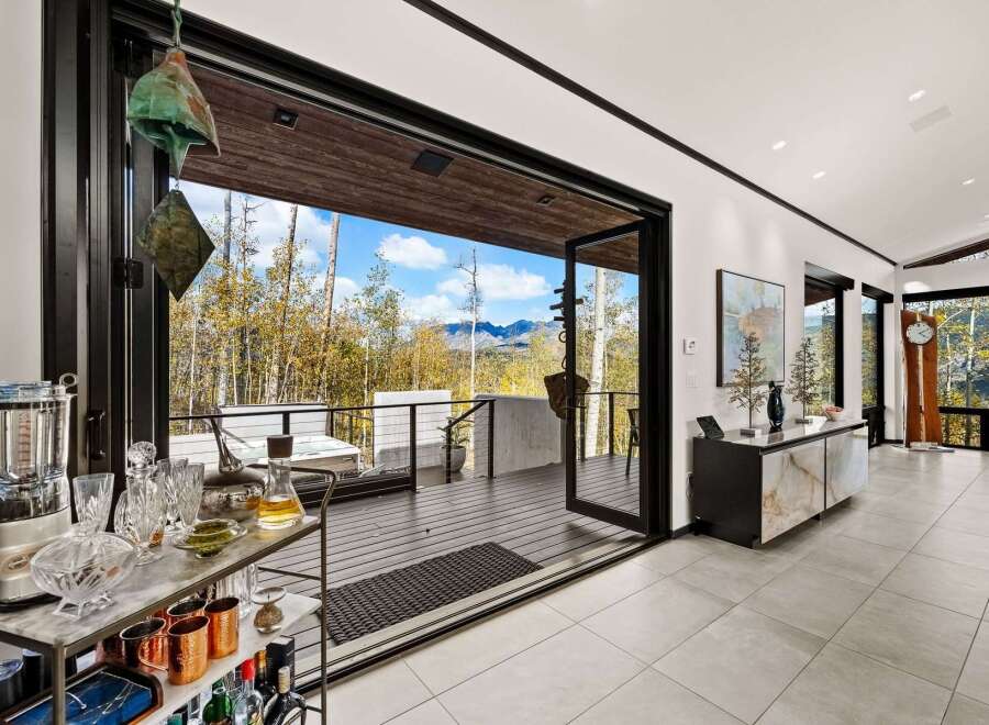 Experience breathtaking mountain views from this stunning modern home, featuring expansive glass doors that open to a spacious deck perfect for entertaining.