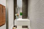 Discover modern elegance in this powder room, featuring a sleek floating vanity and a striking dark tiled accent wall.