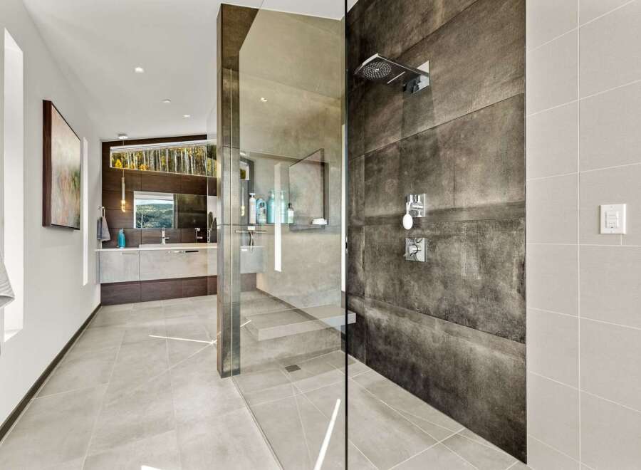 Experience luxury in this modern bathroom featuring a spacious walk-in shower with sleek, dark tile and a rainfall showerhead.