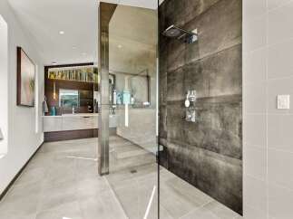 Experience luxury in this modern bathroom featuring a spacious walk-in shower with sleek, dark tile and a rainfall showerhead.