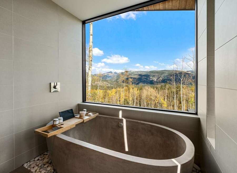 Experience ultimate relaxation in this modern bathroom featuring a freestanding concrete tub with breathtaking mountain views.