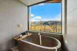 Experience ultimate relaxation in this modern bathroom featuring a freestanding concrete tub with breathtaking mountain views.