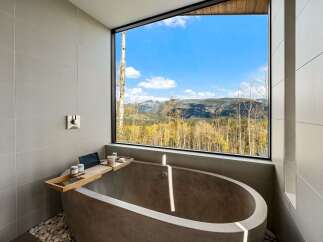 Experience ultimate relaxation in this modern bathroom featuring a freestanding concrete tub with breathtaking mountain views.