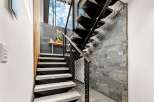Experience modern living with this stunning staircase featuring sleek black metal treads and natural stone accents.
